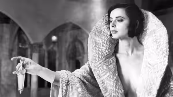 Lisle von Rhuman (Isabella Rossellini) extends a glass while wearing a voluminous robe
