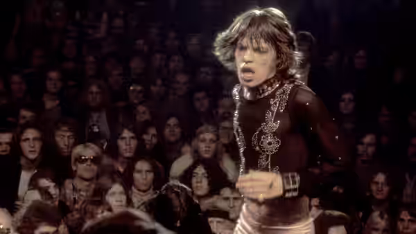 Mick Jagger sings on stage wearing a sequined top before an audience