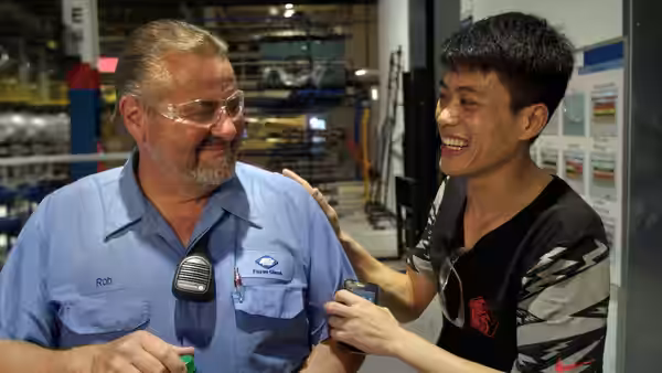 Rob and a young colleague laughing together on the factory floor