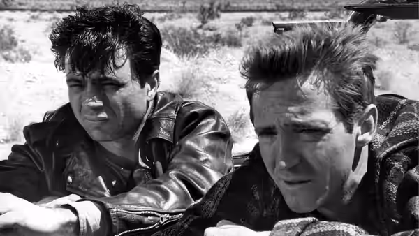 Perry Smith (Robert Blake) and Richard Hickock (Scott Wilson) lie outdoors beside a vehicle
