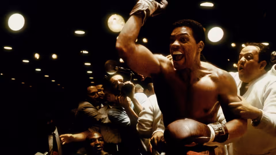 Muhammad Ali (Will Smith) raises a gloved fist as people crowd around him