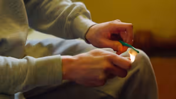 Hands holding a lit match to light a cigarette