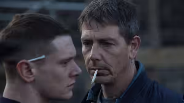 Eric Love (Jack O'Connell) facing Neville Love (Ben Mendelsohn) who holds a cigarette