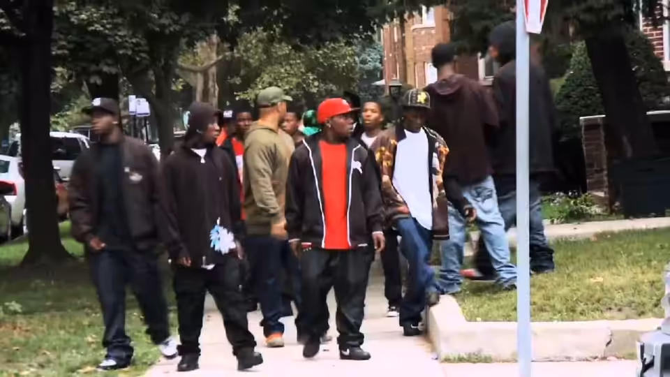 Group of young men walking along a sidewalk in a residential neighborhood