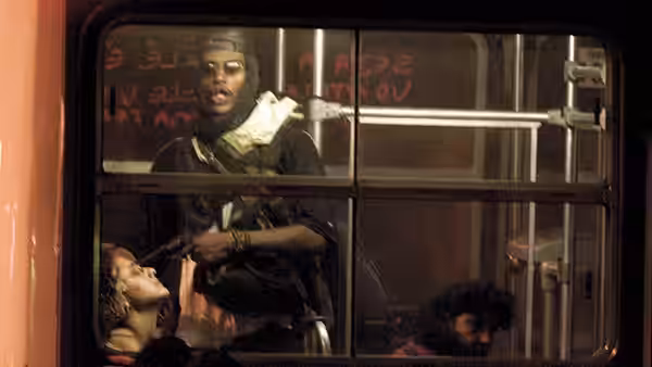 A man stands armed inside a bus while passengers huddle beneath the windows