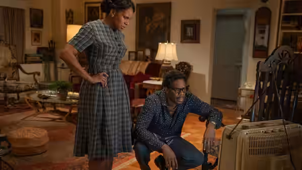 Bayard Rustin (Colman Domingo) sits beside a woman watching television in a living room