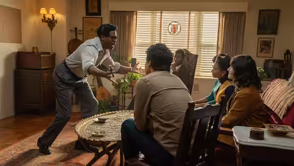 Bayard Rustin (Colman Domingo) gestures animatedly while addressing colleagues in a living room