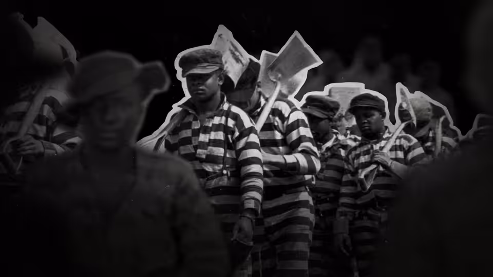 Men in striped prison uniforms holding signs in a crowd