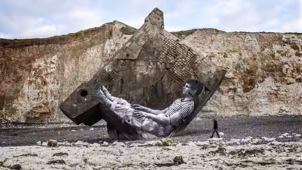 a large reclining figure mural on a cliff with a walker on the beach