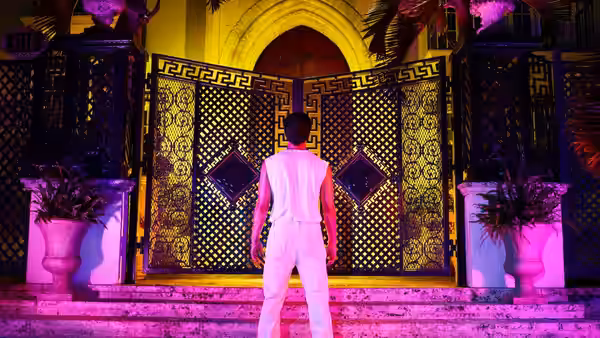 A man in white stands before large ornate golden doors