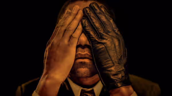 A man covers his face with bare and gloved hands