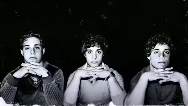 Three young men with curly hair rest their chins on clasped hands