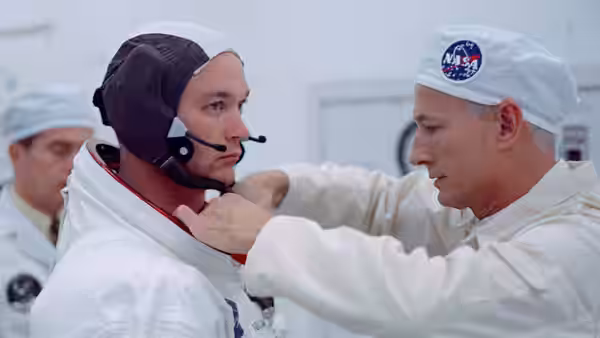 a technician adjusts the helmet of an astronaut during suit preparation
