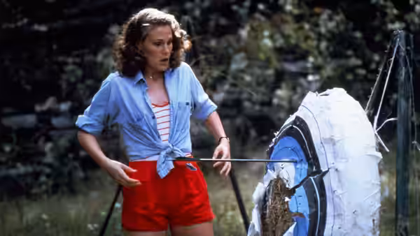 Alice (Adrienne King) stands beside a damaged archery target at the camp