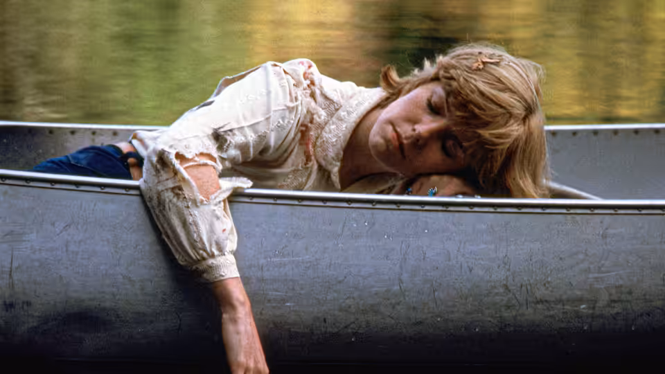 A woman lies slumped over the side of a boat on the lake