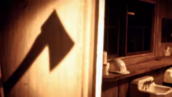 An axe-shaped shadow falls across a bathroom wall beside a sink