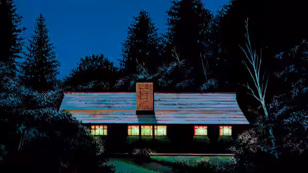 A lit wooden cabin stands among trees at night