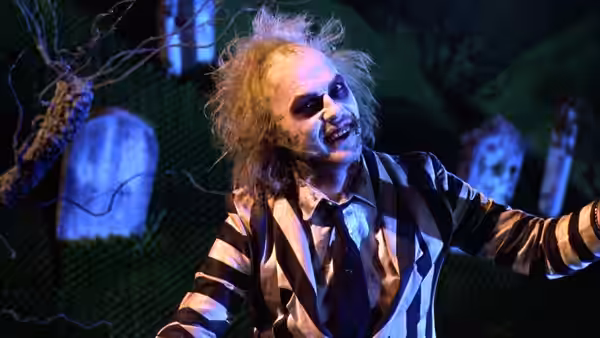 Betelgeuse (Michael Keaton) with arms outstretched in a graveyard at night