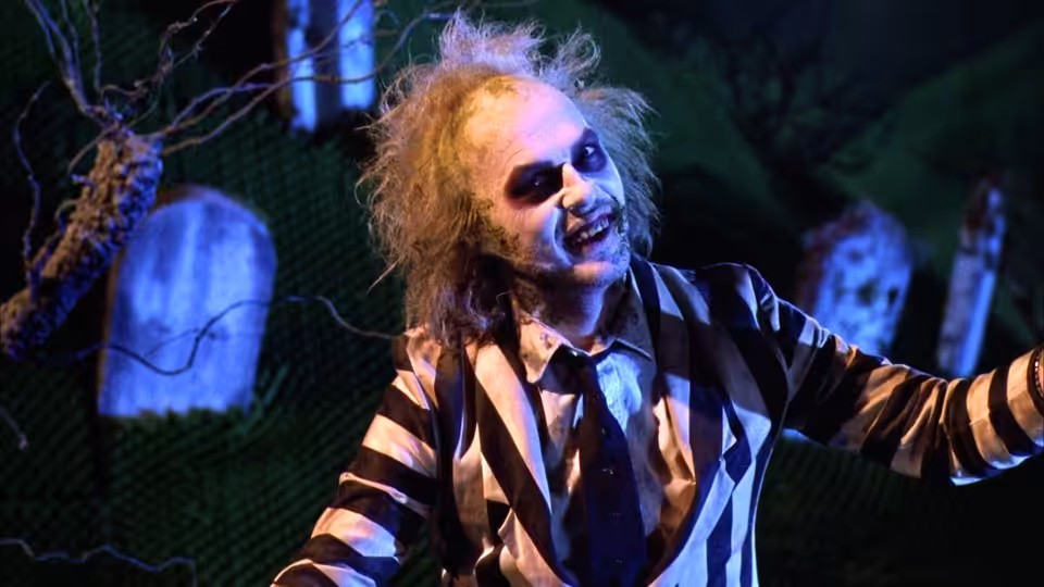 Betelgeuse (Michael Keaton) with arms outstretched in a graveyard at night