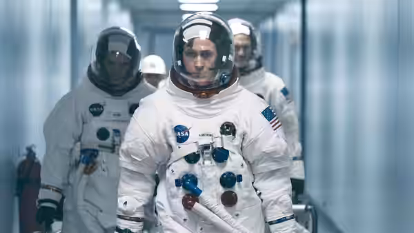 Neil Armstrong (Ryan Gosling) leading astronauts down a corridor in spacesuits