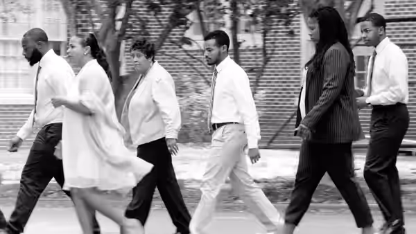 Six adults in business attire walking together along an outdoor path