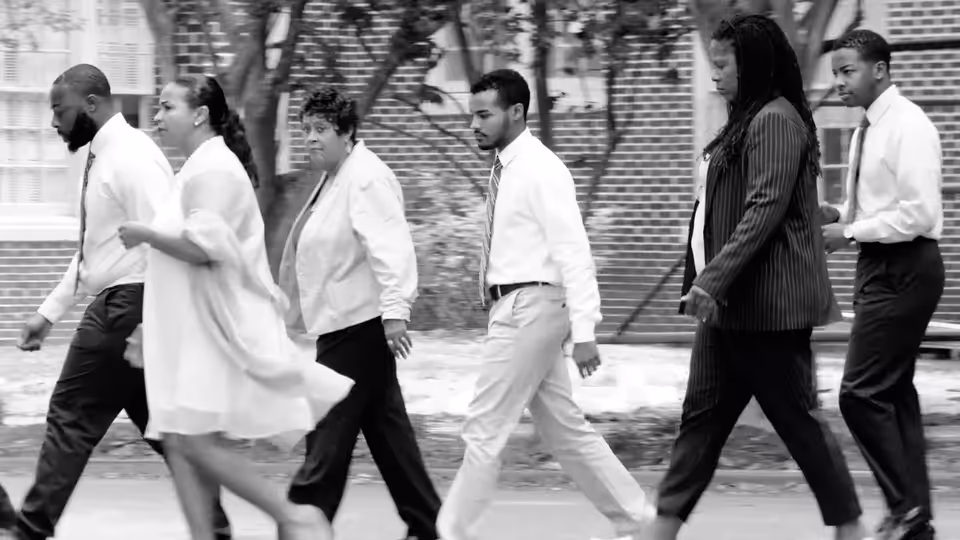 Six adults in business attire walking together along an outdoor path