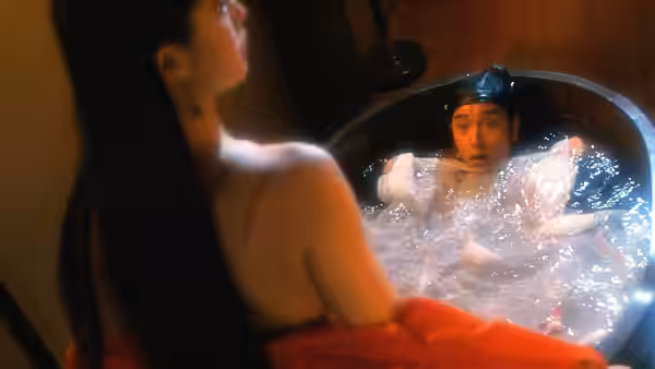 Ling Choi-san (Leslie Cheung) sits startled in a bath as a woman watches