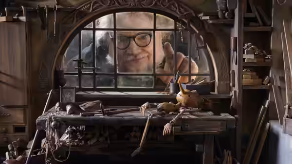 Geppetto (David Bradley) peering through the window of his wooden workshop