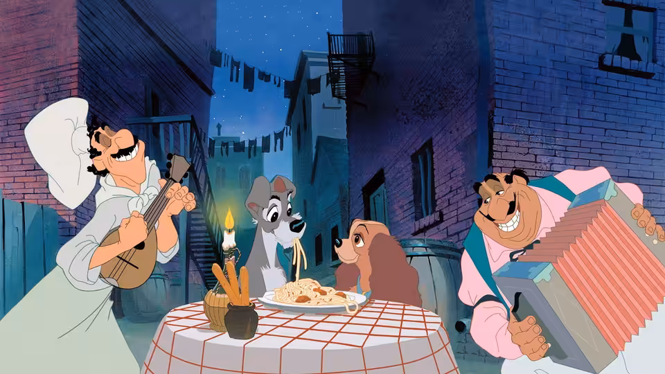 A chef and accordion player serenade two dogs sharing spaghetti at a table