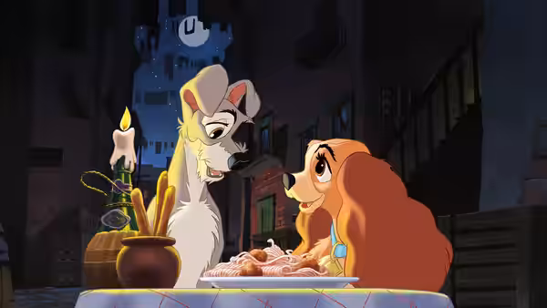 Tramp and Lady sit together at a candlelit table with a plate of spaghetti