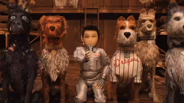 Boy in silver suit kneels among five dogs in a wooden interior