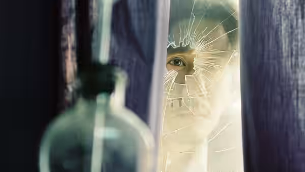Close-up of an eye peering through a shattered pane of glass