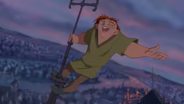 Quasimodo clings to a pole high above the city with arms outstretched at dusk