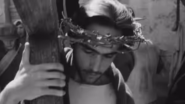 Cristo wears a crown of thorns and leans against a wooden post