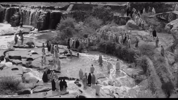 Crowds gather beside pools and waterfalls in a rocky landscape