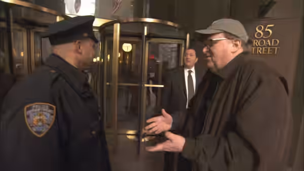 Michael Moore gestures while speaking to a police officer outside a building