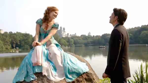 Giselle sits on a rock in a turquoise gown while Robert stands nearby