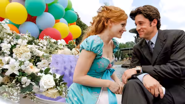 Giselle and Robert smile at each other beside colorful balloons and flowers