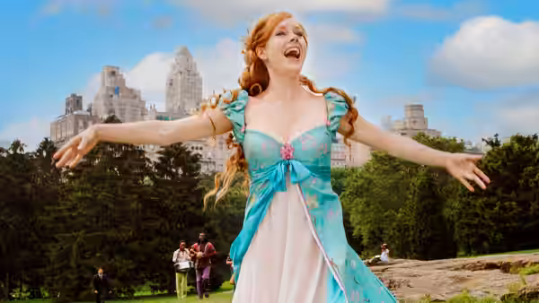 Giselle stands with arms outstretched in a park overlooking the city
