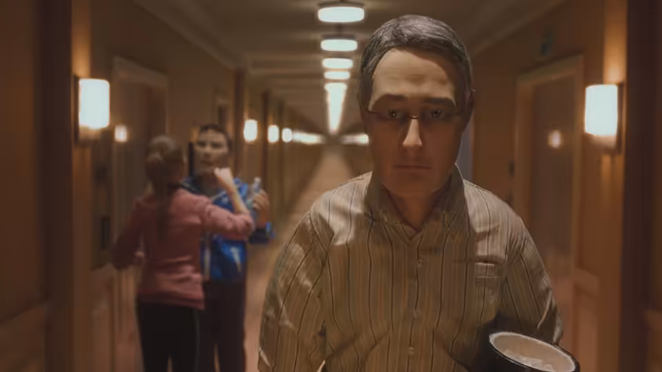 Michael Stone (David Thewlis) walking down a hotel hallway with coffee