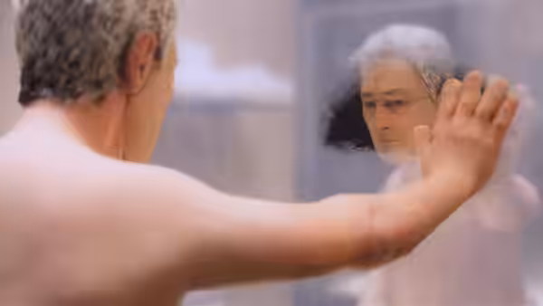 Michael Stone (David Thewlis) pressing his hand against a mirror