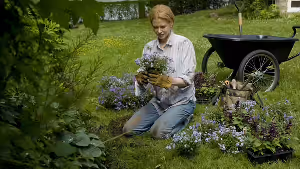 Becca (Nicole Kidman) kneeling in a garden holding potted flowers