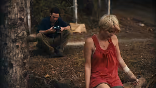 Andrew (Scoot McNairy) sitting with a camera while Samantha (Whitney Able) rests nearby