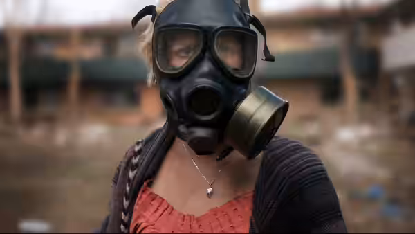 Samantha (Whitney Able) wearing a gas mask and looking straight ahead