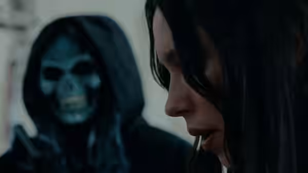 woman looking down as a hooded skull figure stands behind her