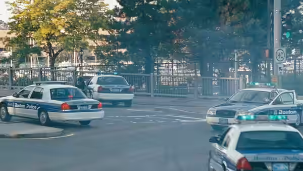 Boston police cars with lights on parked at a city intersection