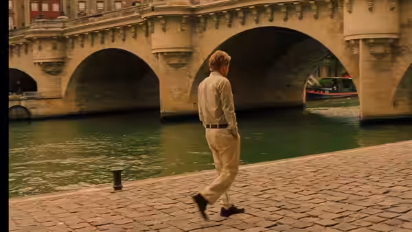 Gil (Owen Wilson) walking on a cobblestone path by the river