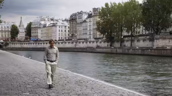 Gil (Owen Wilson) walking along a riverbank in Paris