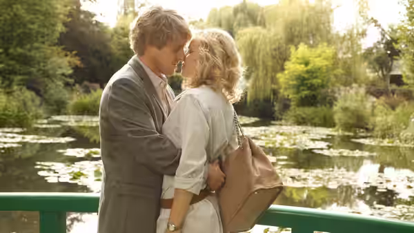 Gil (Owen Wilson) and Inez (Rachel McAdams) embracing on a park bridge
