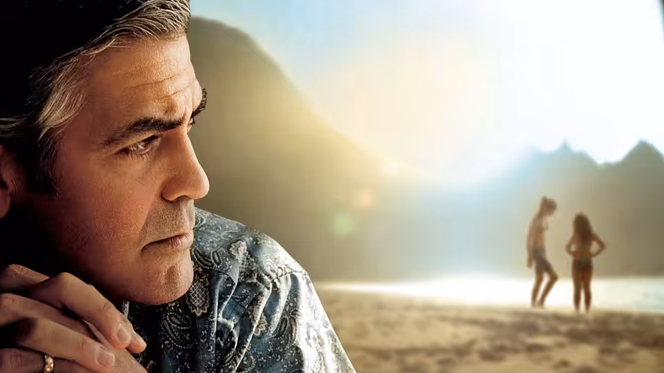 Matt King (George Clooney) on the beach looking toward two figures in the distance